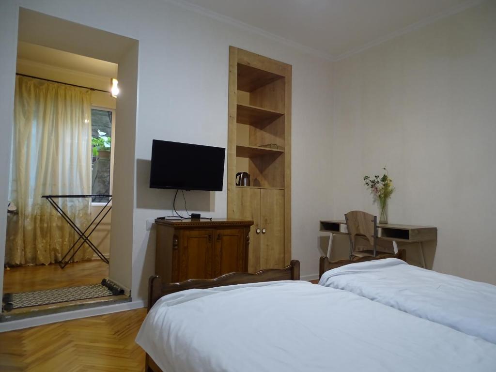 een slaapkamer met 2 bedden en een flatscreen-tv bij Vake Super Quiet and Comfy Apartment with a Yard in Tbilisi City