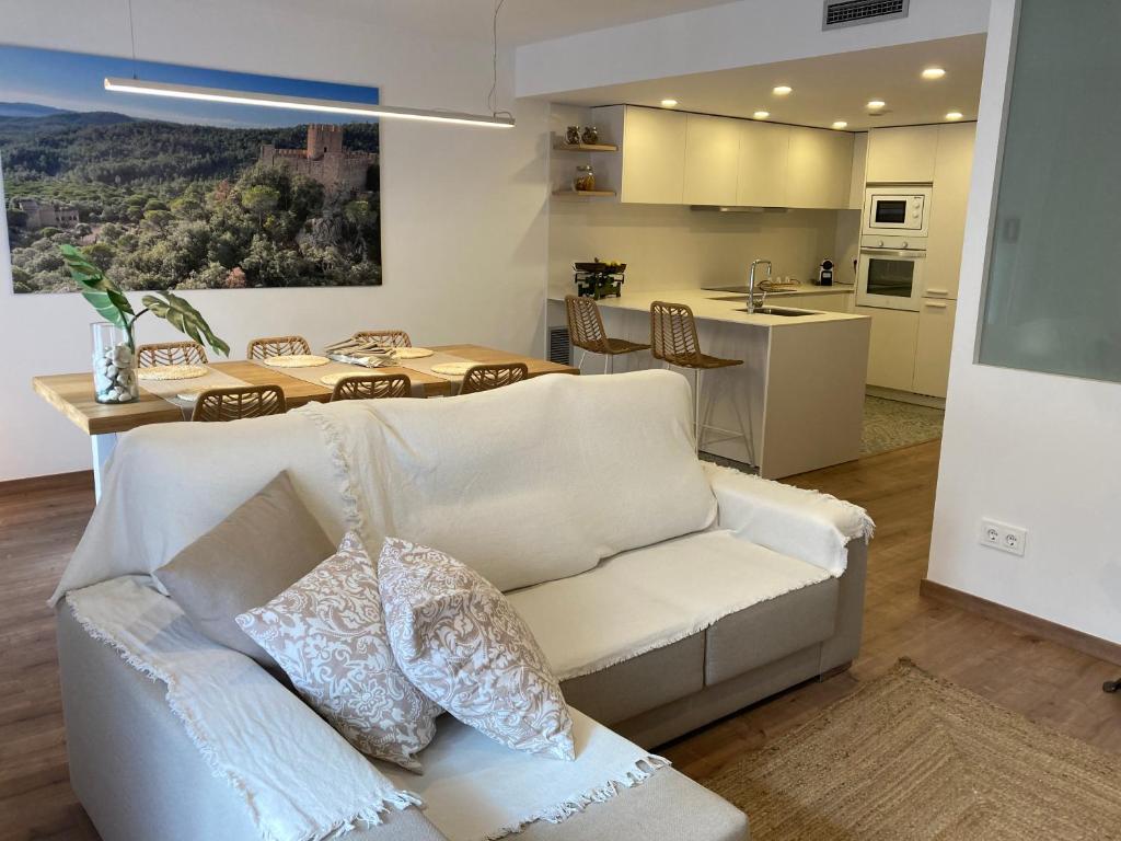 een woonkamer met een witte bank en een keuken bij Apartamento céntrico, climatizado y totalmente equipado de 3 habitaciones para 6-7 personas in Santa Coloma de Farners