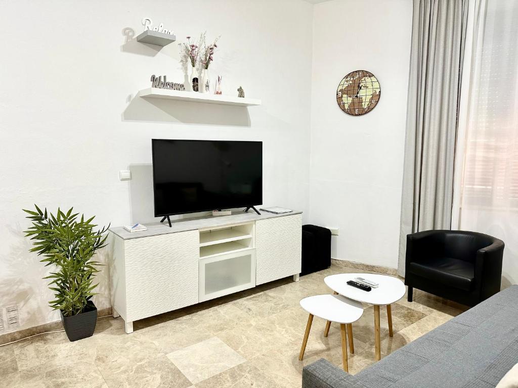 una sala de estar con TV de pantalla plana en un armario blanco en Apartamento acogedor y moderno en pleno centro de Sevilla con Parking Gratis, en Sevilla