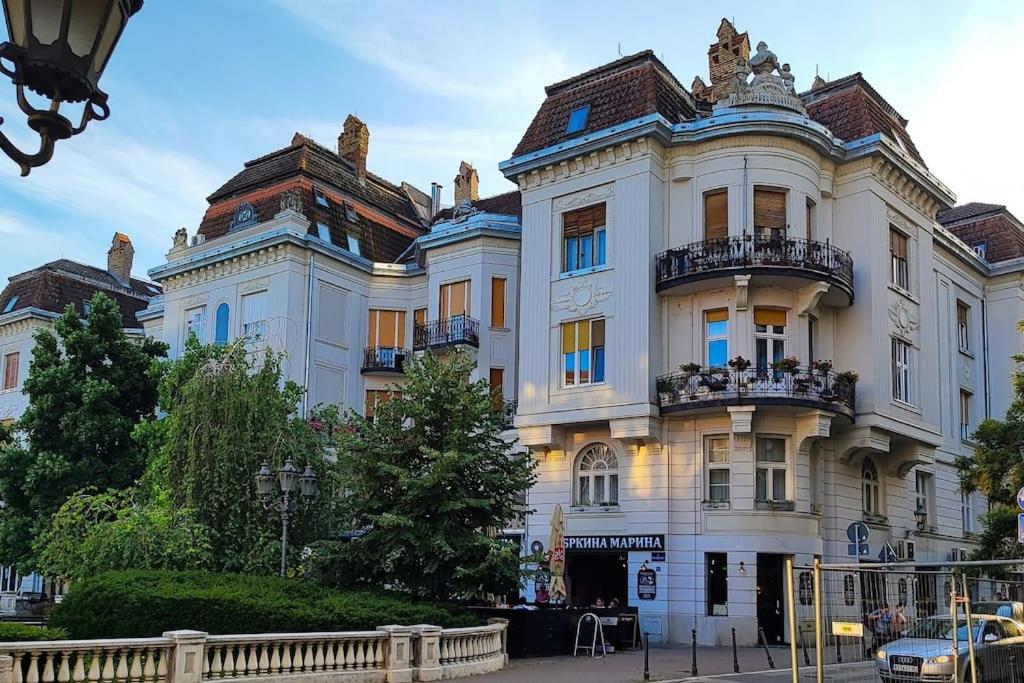 ein großes weißes Gebäude mit zwei Balkonen auf einer Straße in der Unterkunft FilinHome Trg Mladenaca in Novi Sad