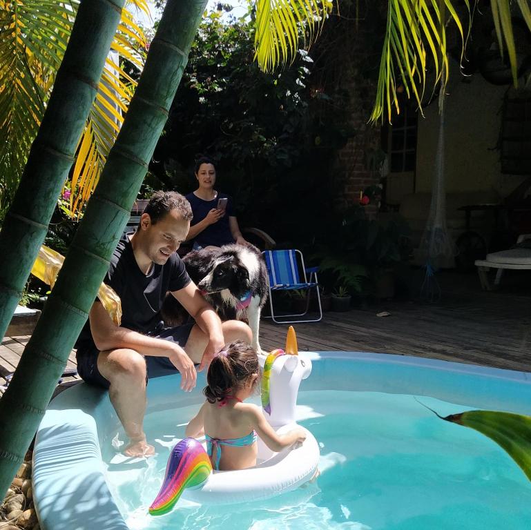 ein Mann und ein Mädchen in einem Swimmingpool mit einem Hund in der Unterkunft Pousada Villa da Nascente in Florianópolis