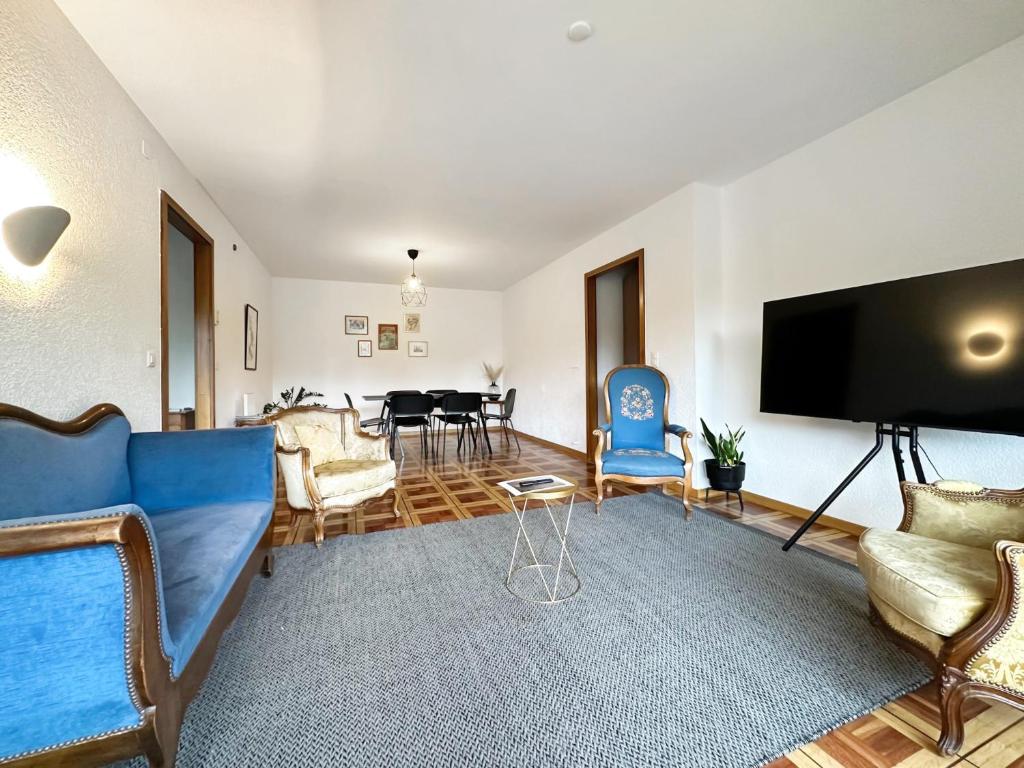 a living room with a blue couch and a tv at Castelview - Sion next to the old town in Sion