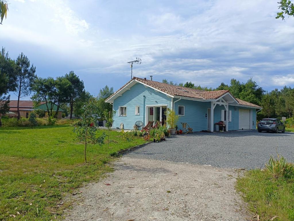 une maison bleue avec une voiture garée dans l'allée dans l'établissement Pause nature au cœur du parc naturel du Médoc, à Moulis-en-Médoc