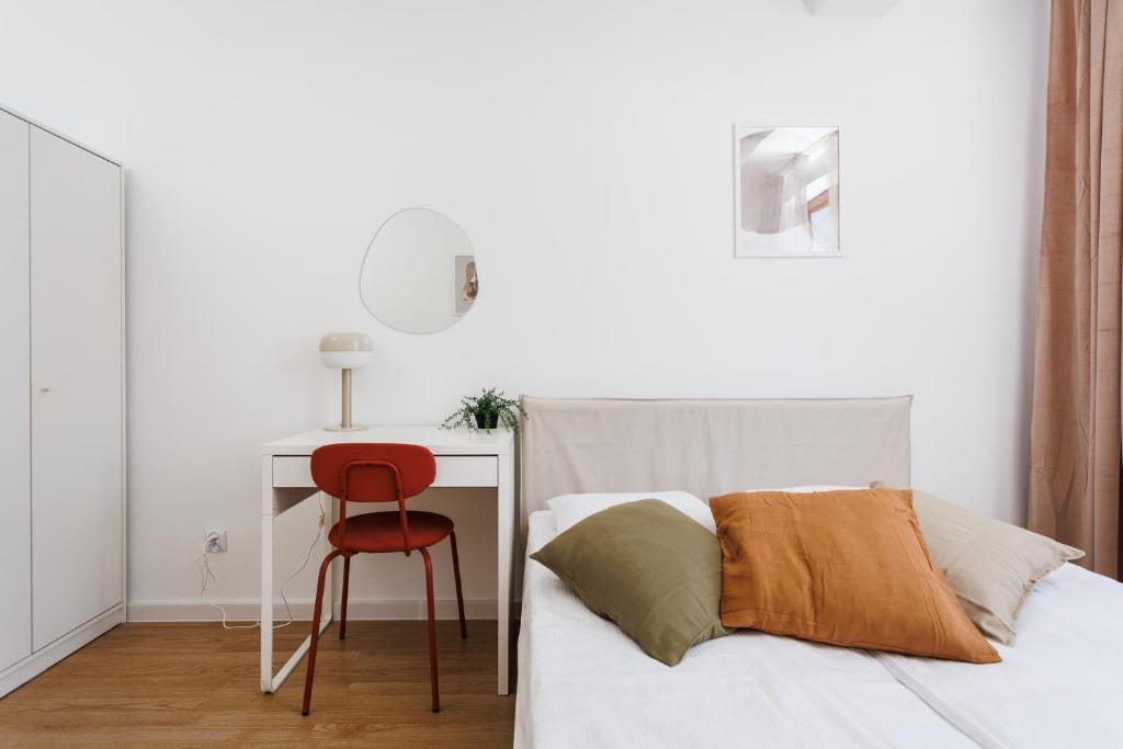 een slaapkamer met een bed met een rode stoel en een bureau bij Pretty 4 Bedroom Apartment x Parking Spot x City Center in Krakau