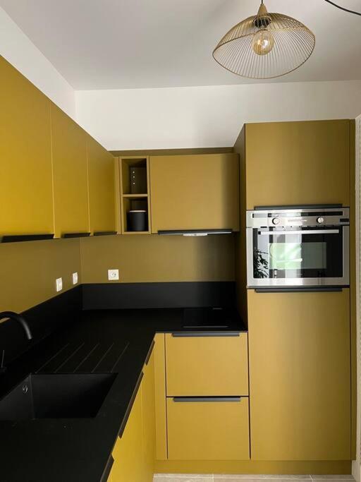 a kitchen with yellow cabinets and a stove top oven at L&#39;Oasis urbaine : détente totale in La Rochelle