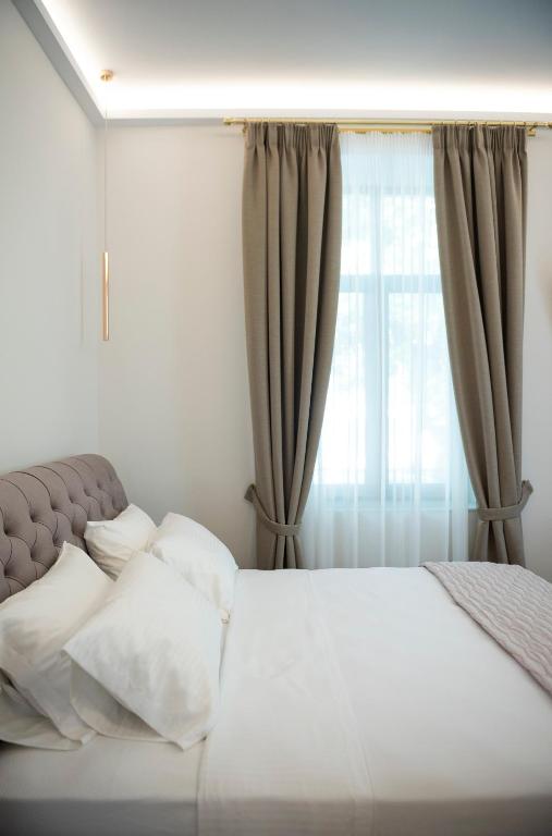 a bedroom with a white bed with a window at Jensen Luxury Suites in Rhodes Town