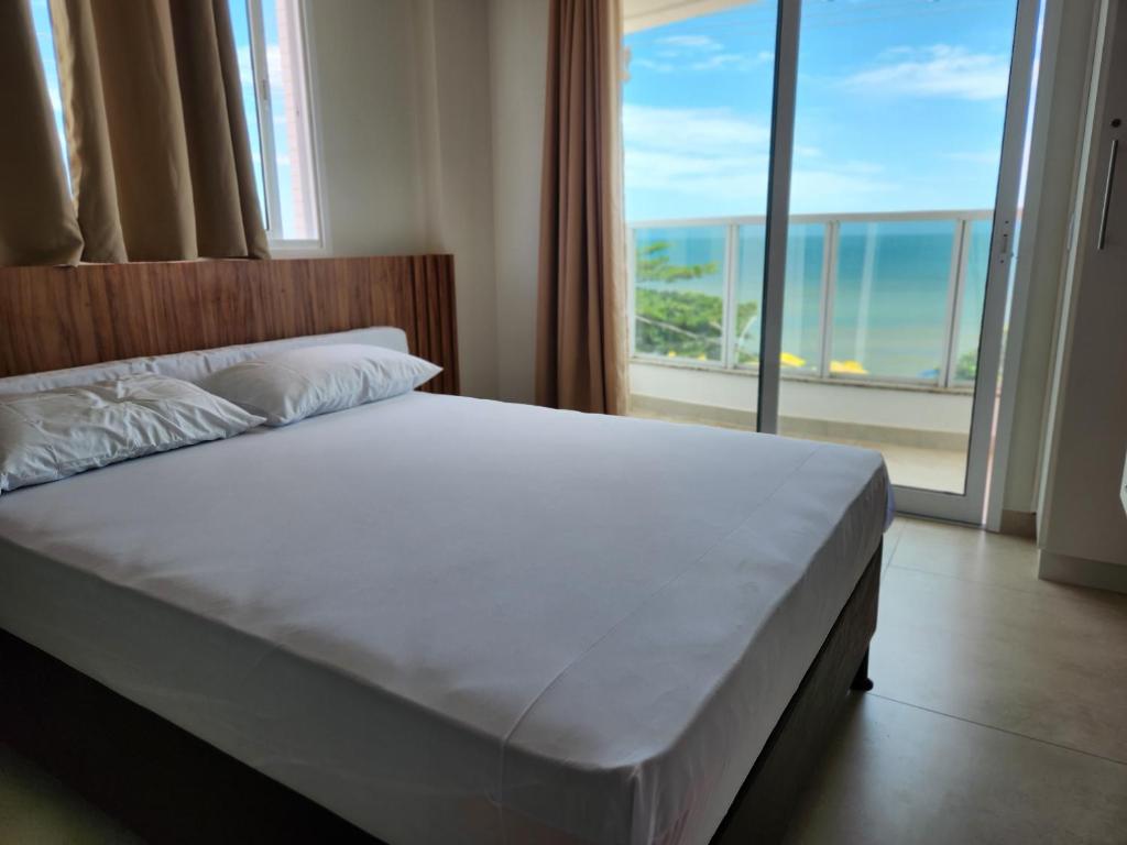 a bedroom with a bed with a view of the ocean at Apto frente mar 3 suites Castelhanos ES in Anchieta