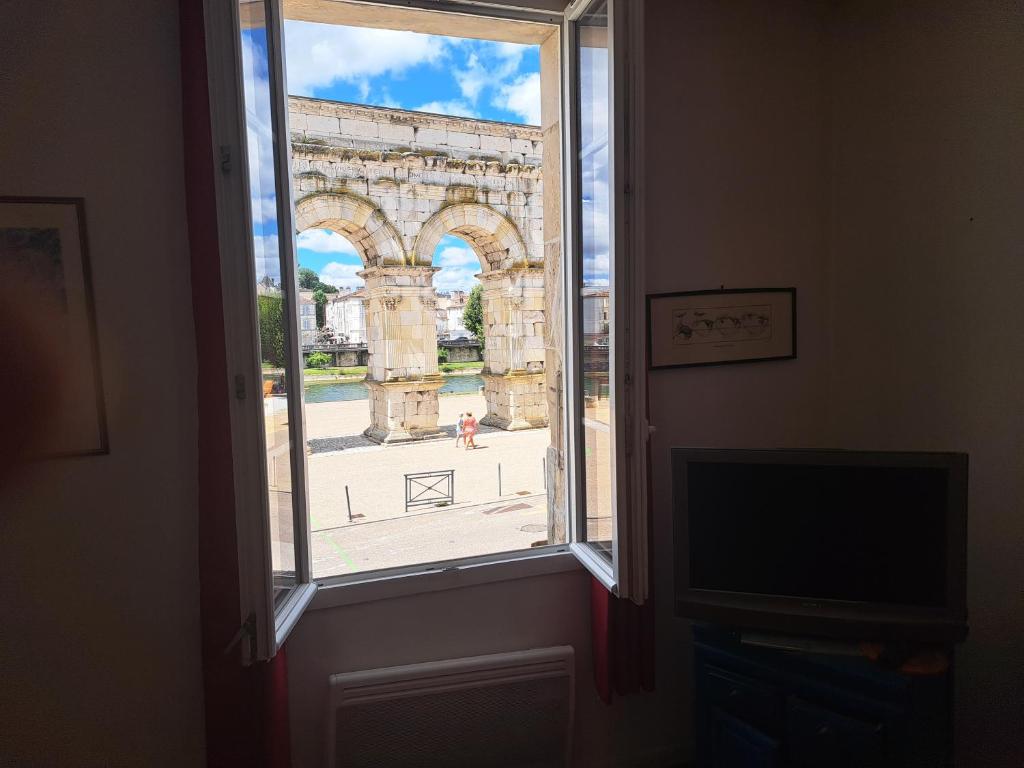 uma janela aberta com vista para o arco do triunfo em Loft vue imprenable sur le vieux Saintes em Saintes