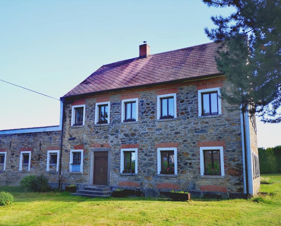 ein altes Backsteinhaus mit weißen Fenstern auf einem Feld in der Unterkunft Relax v Jizerkách in Nové Město pod Smrkem