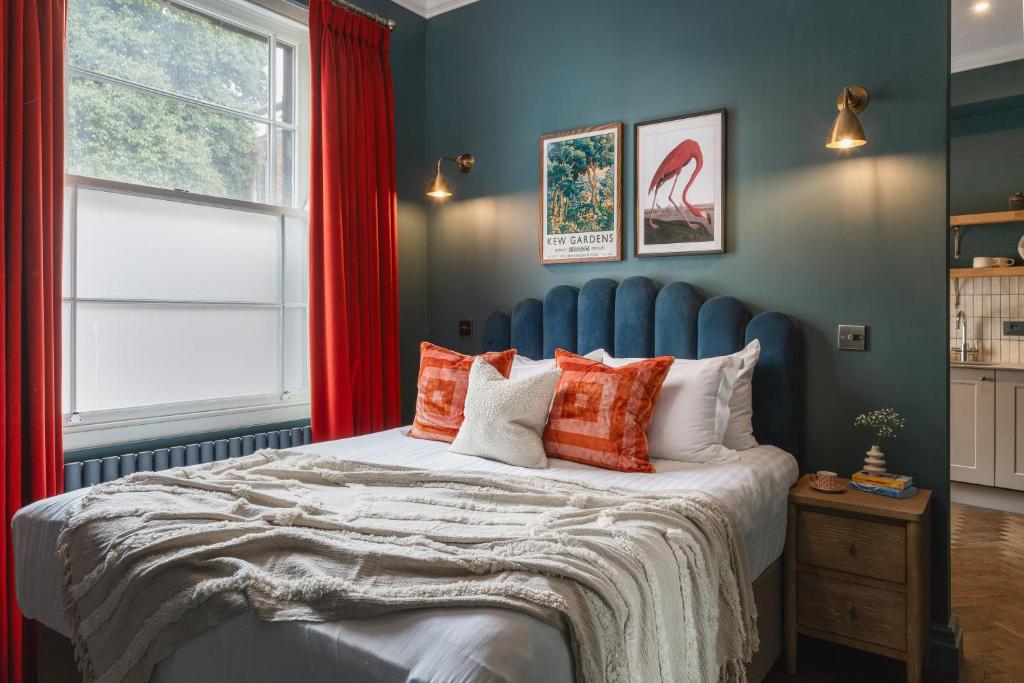 a bedroom with a large bed with red curtains at The Cotham Arms Apartments in Bristol