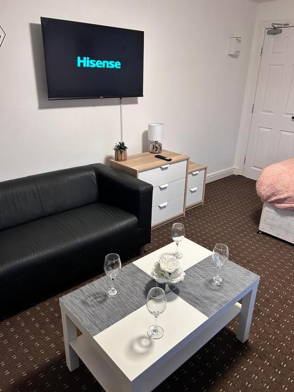 uma sala de estar com um sofá e uma mesa com copos de vinho em Bv Cozy Deighton Studio with Free Parking - Budget-Friendly Stay em Huddersfield