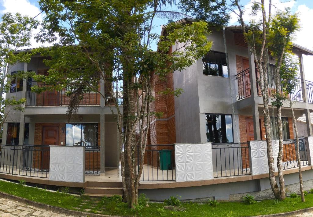 an apartment building with trees in front of it at Chalés Estrada Real in Conceição da Ibitipoca