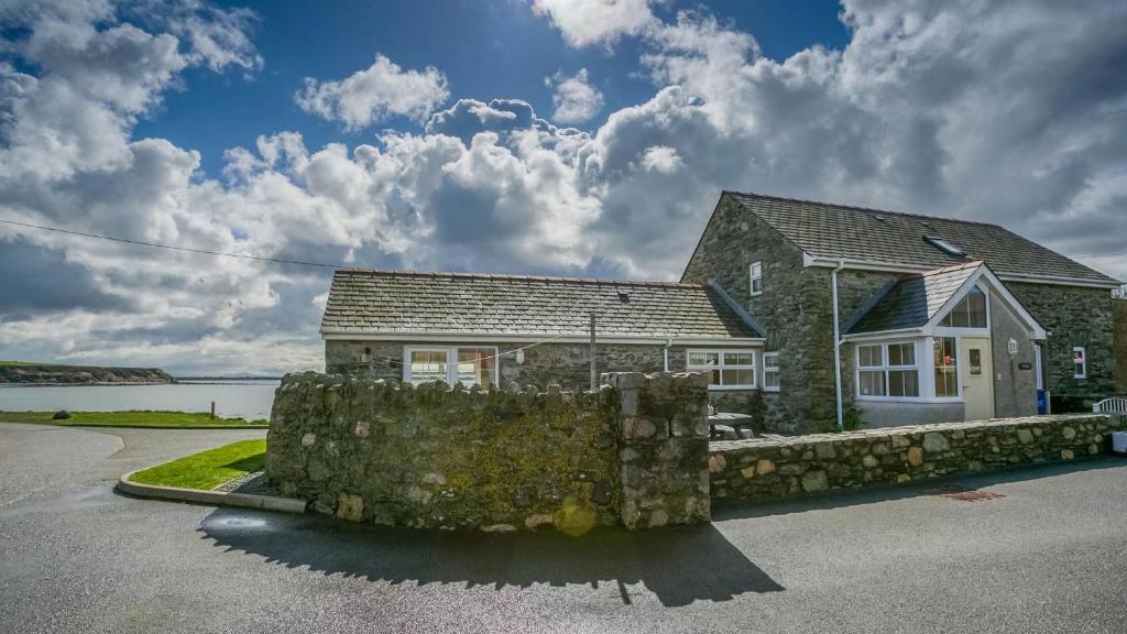 a house with a stone wall in front of it at Efail Penrhyn in Llanfachraeth