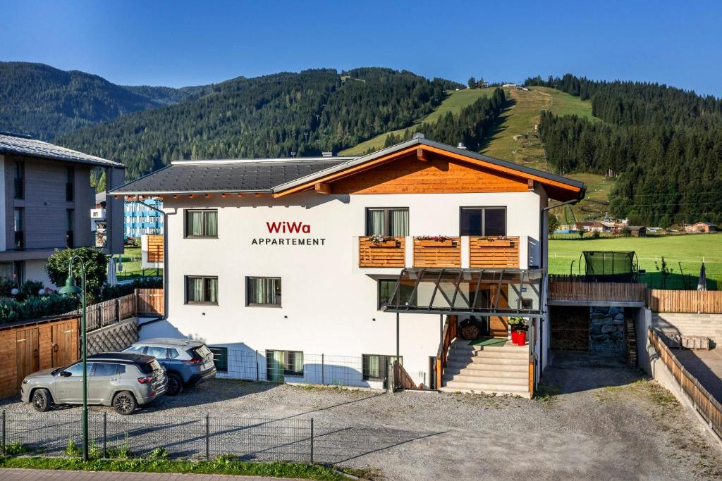 a house with a balcony and a car parked in a parking lot at WiWa Appartement in Flachau