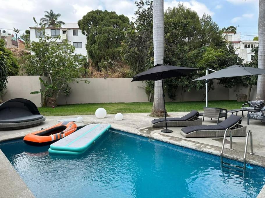 een zwembad met een vlot, stoelen en parasols bij Casa privada en Villa Bricia in Cuernavaca