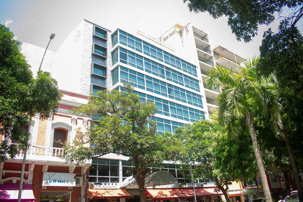 un edificio alto con árboles delante de él en HOTEL MANZUR en Barranquilla