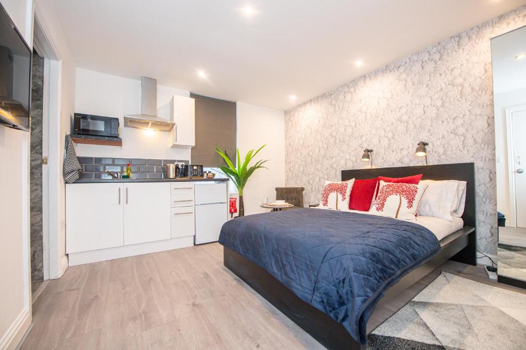 a bedroom with a large bed and a kitchen at The Blossoms Studio Apartments in Liverpool