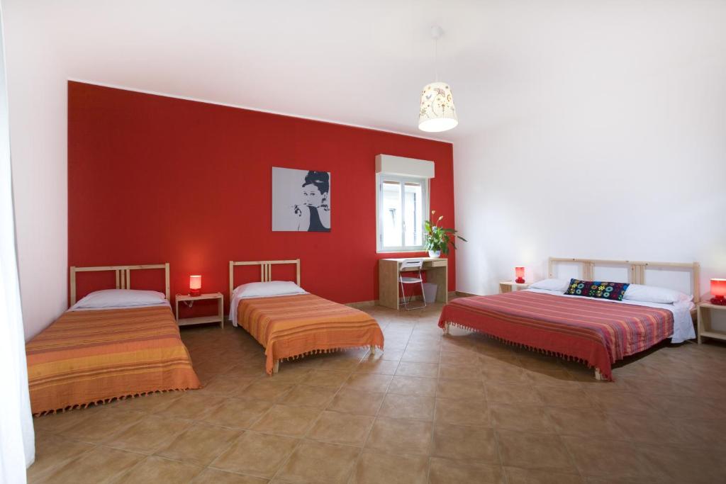 a room with two beds and a red wall at B&B La Gatta Bianca in Oliveri