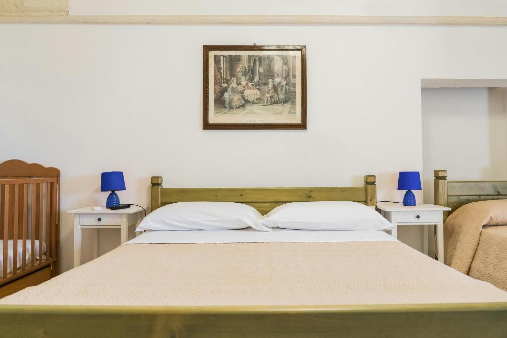 ラテルツァにあるSan Leonardo - ApartHotelのベッドルーム1室(ベッド1台、テーブル2台付)、壁の絵画が備わります。