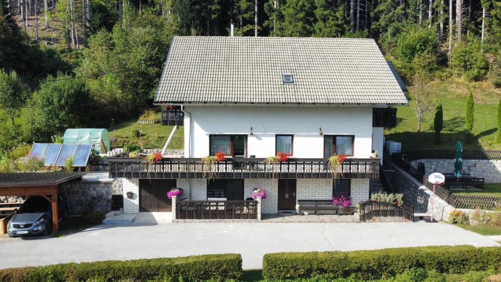 a white house with a balcony with flowers on it at Apartma Vidovič in Rateče