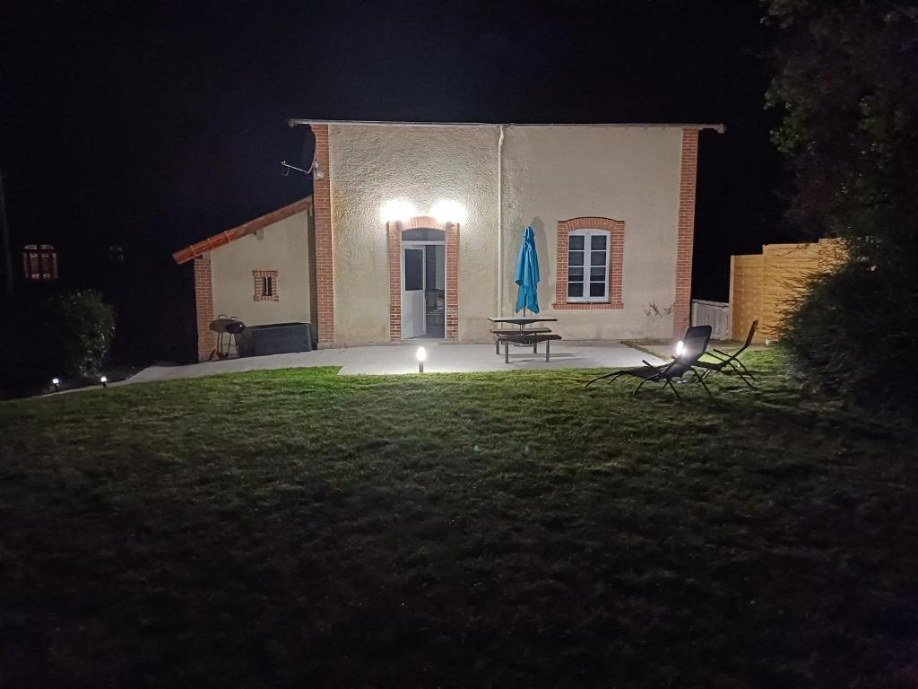 a house at night with a picnic table in the yard at Gîte garde-barrière 2 chambres in Saint-Guen