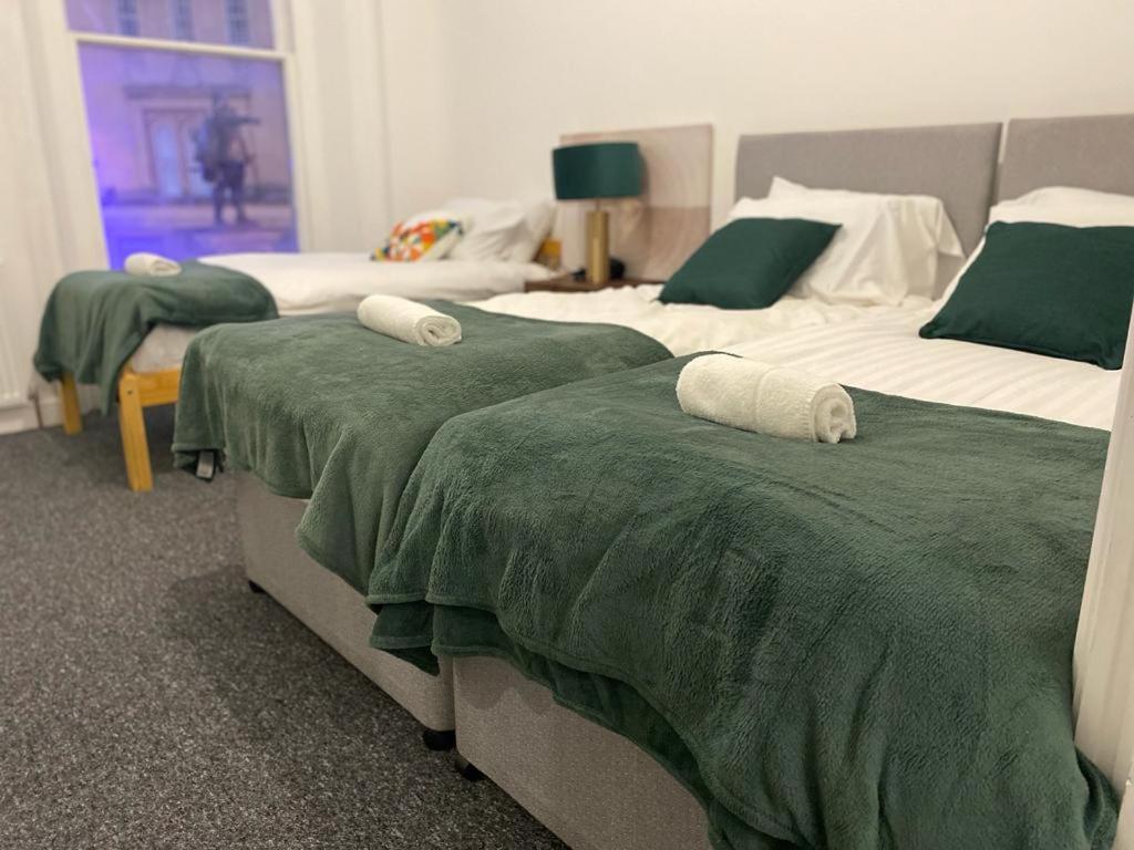 twee bedden in een kamer met groene en witte dekens bij Home in Bridgwater