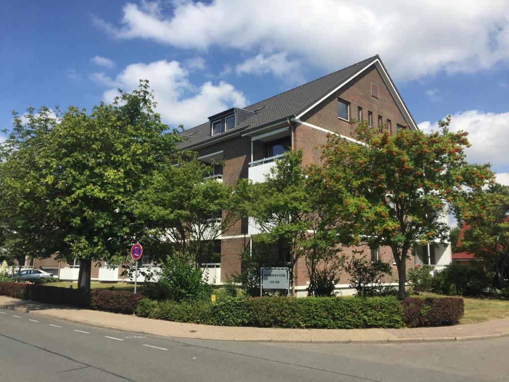 um edifício de tijolos com árvores em frente a uma rua em FeWo Nordseestraße em Büsum