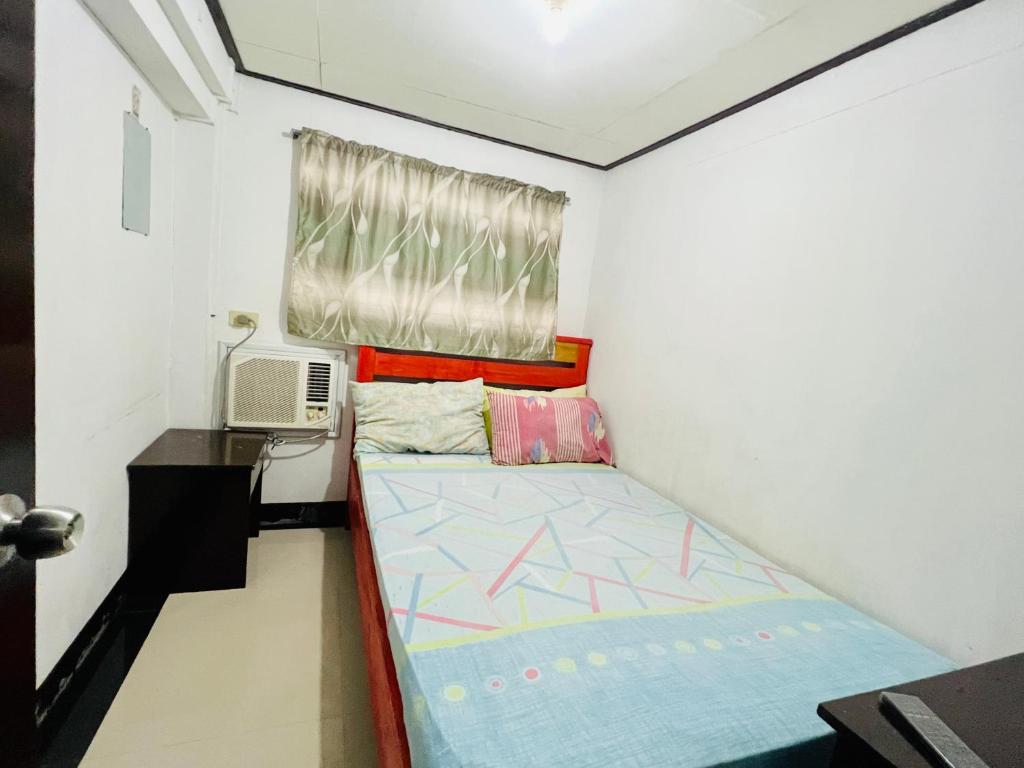 Habitación pequeña con cama y ventana en King Henry's Transient House, en Bantay