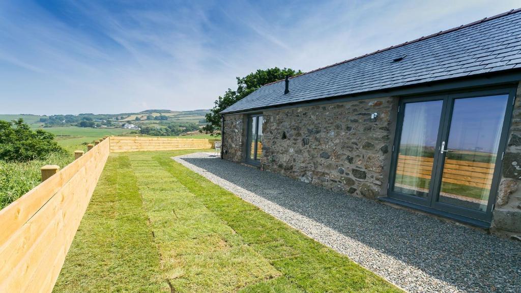 a stone house with a wooden fence next to it at Hebog in Llanrhwydrys