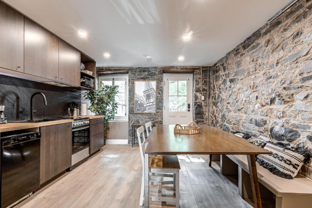 魁北克市的住宿－Beautiful Vieux 2 Bedroom Apt，厨房配有桌子和石墙