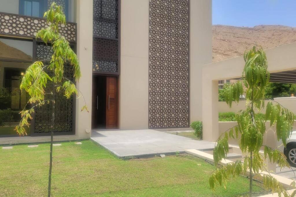 ein Haus mit einem Baum vor einem Gebäude in der Unterkunft muscat bay nameer villa in Muscat