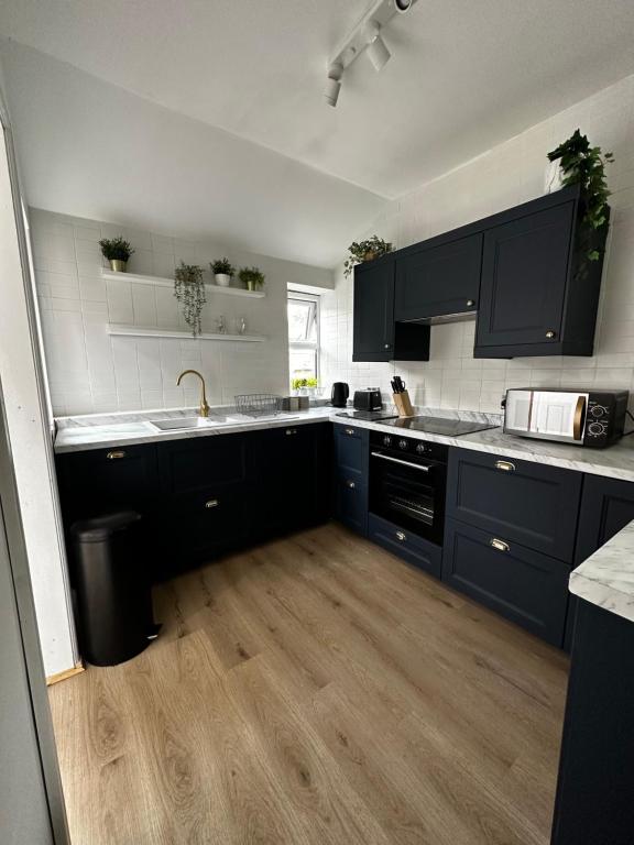 a kitchen with blue cabinets and a wooden floor at Flat 2 The Butlers Quarters in Oswestry