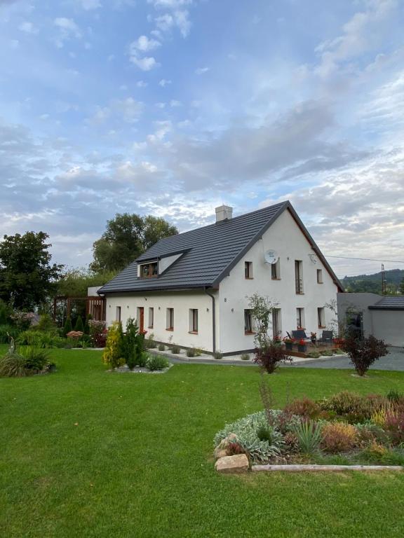 une maison blanche avec un toit noir sur une cour dans l'établissement Apartamenty Leśna Osiem, à Jeżów Sudecki