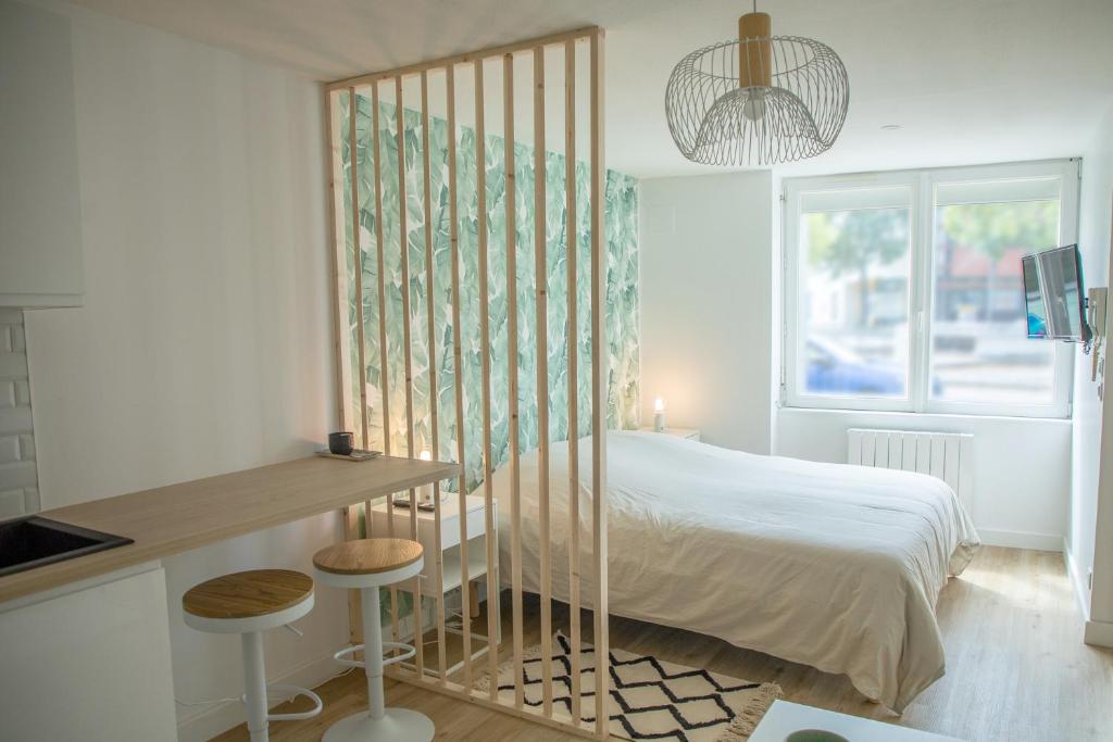 a bedroom with a bed and a table and a window at Le Jade - Appart'Escale in Saint-Nazaire