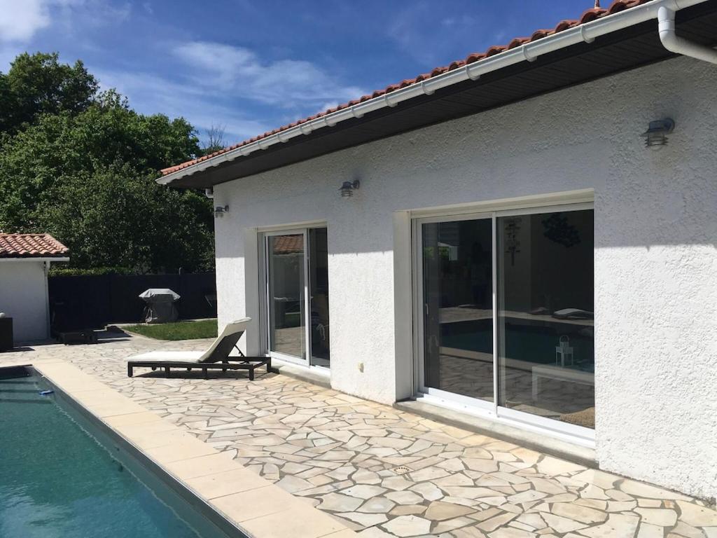 une maison avec une piscine et un banc à côté dans l'établissement Villa familiale piscine-Océan & Bassin d'Arcachon, à Le Porge