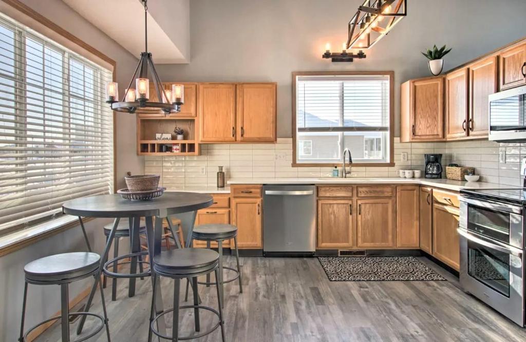a kitchen with wooden cabinets and a table and stools at Welcoming West Fargo Retreat w Backyard in West Fargo