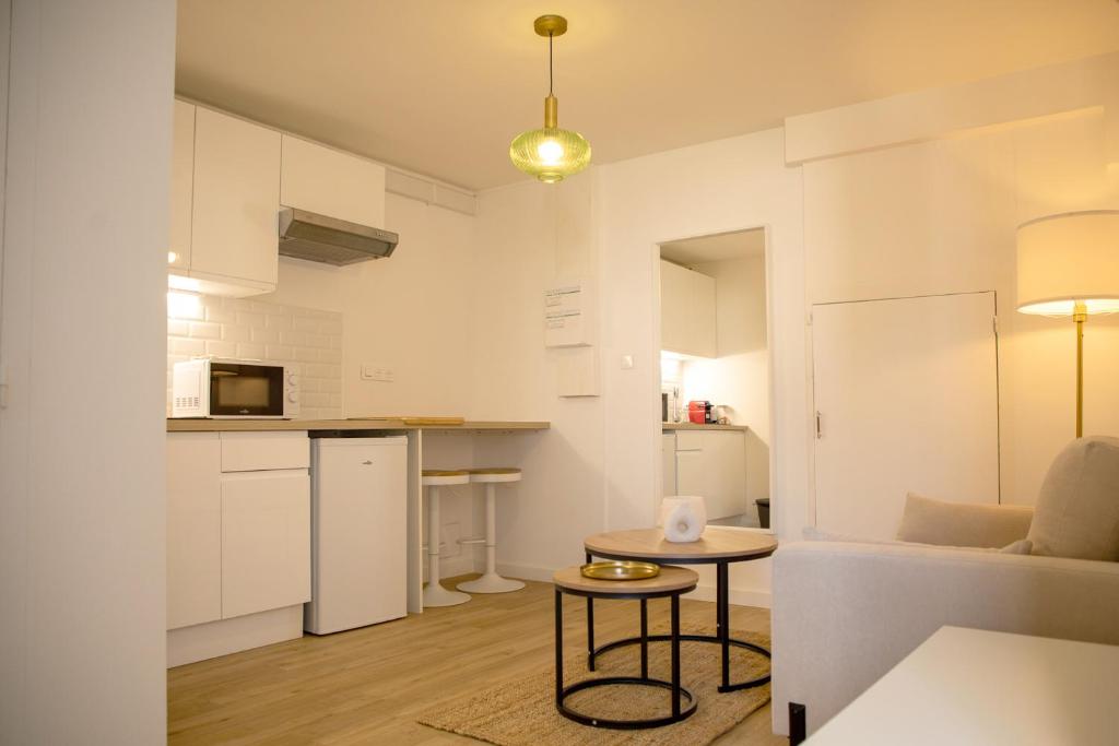 a kitchen and living room with white cabinets and a table at Le Marais - Appart'Escale in Saint-Nazaire