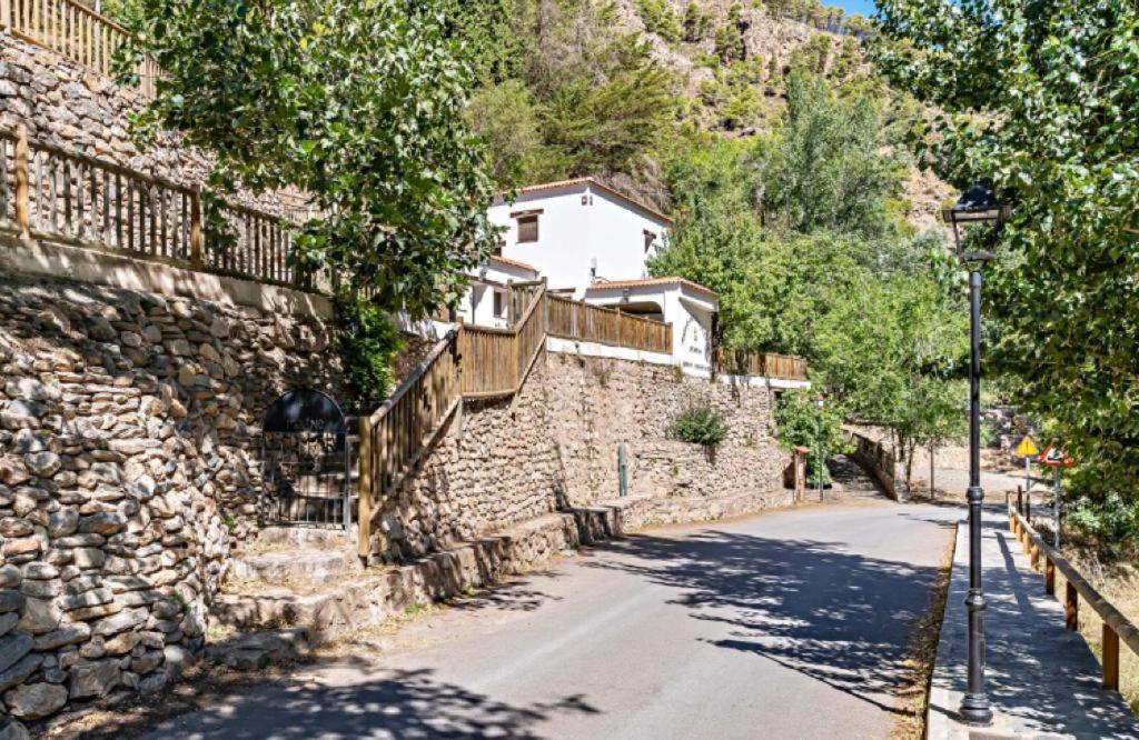 una calle con una pared de piedra y un semáforo en Molino del Nacimiento en Laujar de Andarax