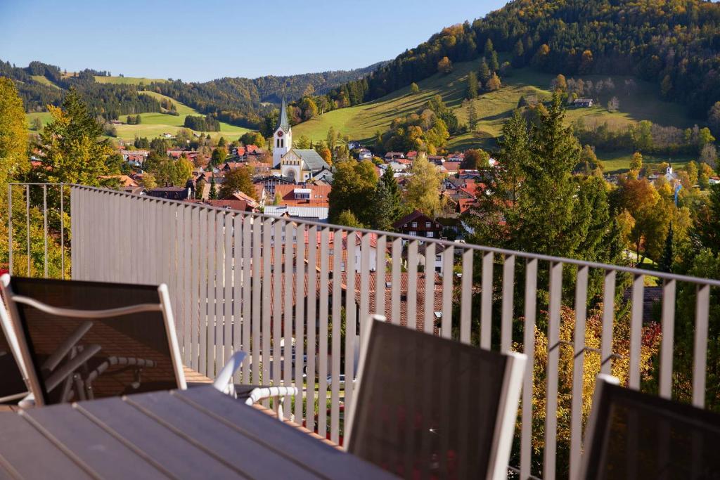 a table and chairs on a balcony with a view of a town at Staufen Chalets am Kalvarienberg in Oberstaufen