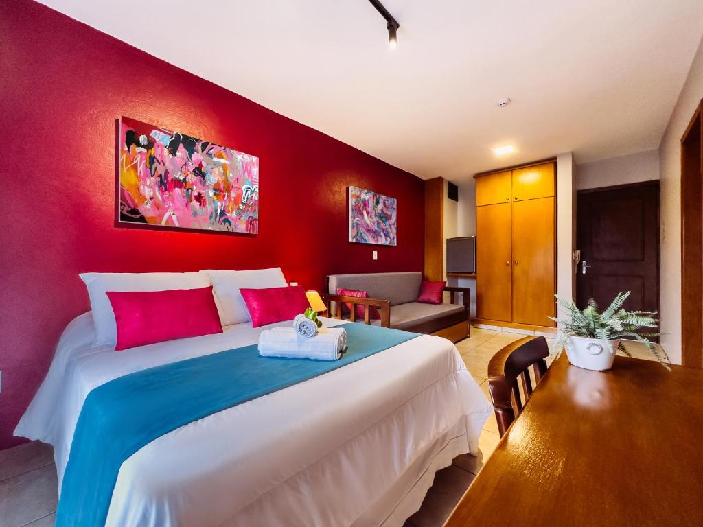1 dormitorio con 1 cama grande y pared roja en Luzzy Hotel en Canela