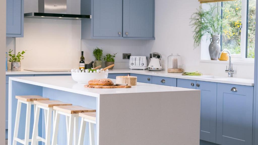 a kitchen with blue cabinets and a white counter top at Sirusa in Trearddur