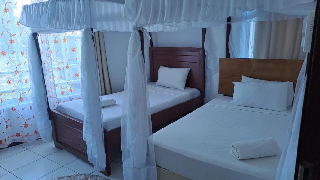 um pequeno quarto com duas camas e cortinas em Crystal beach apartment em Mombasa