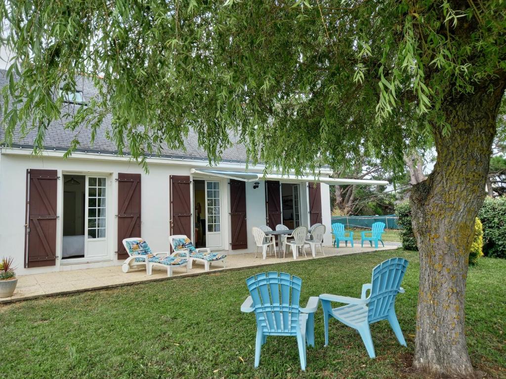 una casa con sillas azules y un árbol en maison de l ile, en Damgan