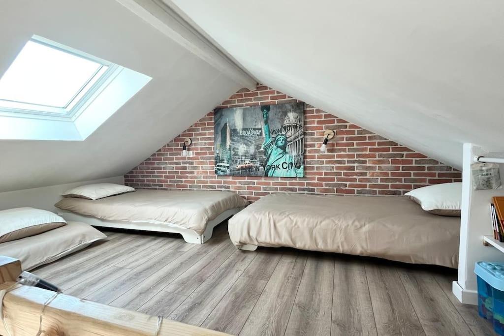 um quarto no sótão com 2 camas e uma parede de tijolos em L'échappée MERs- Maison 3 chambres au Centre 500m de la plage em Mers-les-Bains