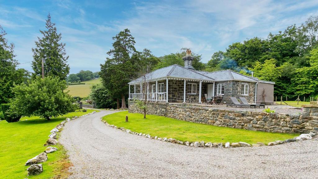 a stone house with a gravel road leading to it at Cae Mab Dafydd in Llanfairfechan