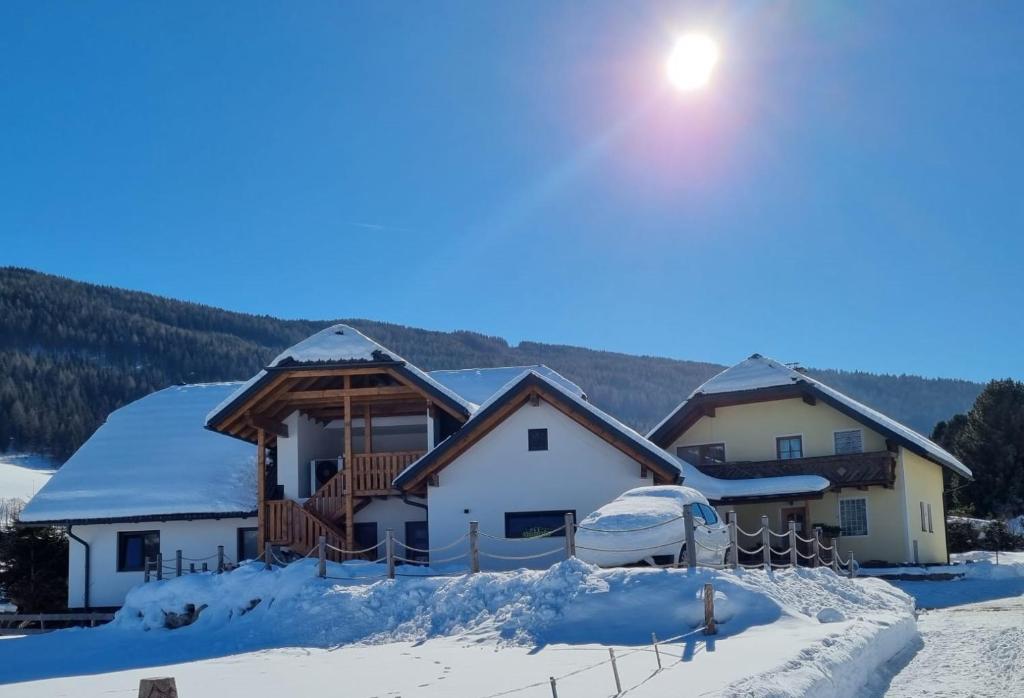 a house in the snow with the sun in the sky at Das Dorfnest in Sankt Margarethen im Lungau