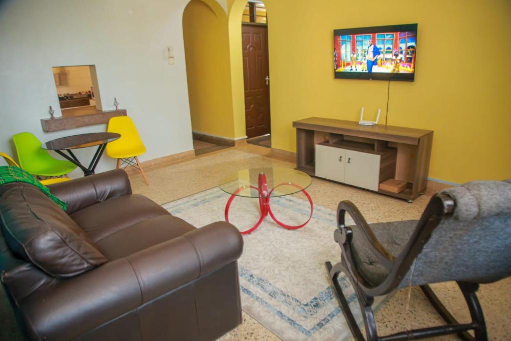 een woonkamer met een bank en een tv bij Asya Homes in Mombasa