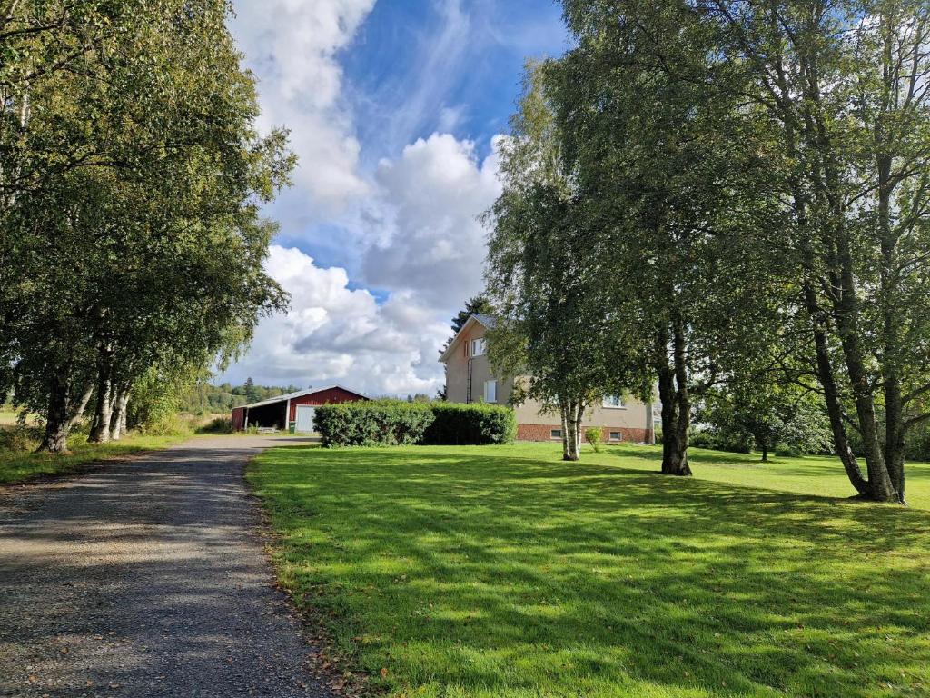 una carretera en un campo con árboles y una casa en Serenity Cottage 2 en Närpiö