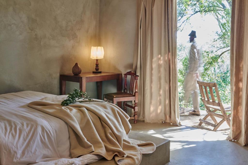 a bedroom with a bed and a table and a window at FARMHOUSE58 in Krugersdorp
