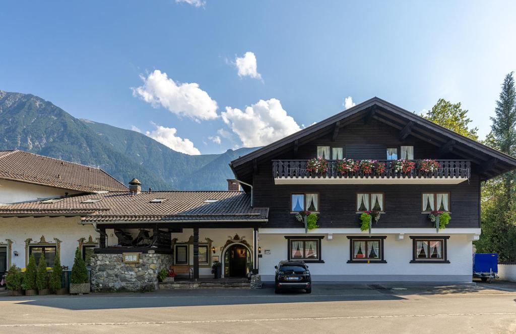 un grand bâtiment en bois avec une voiture garée devant. dans l'établissement Hotel Alpenhof, à Oberau